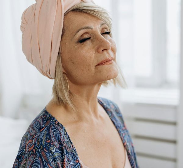 Calm person meditating peacefully with eyes closed in a serene setting.