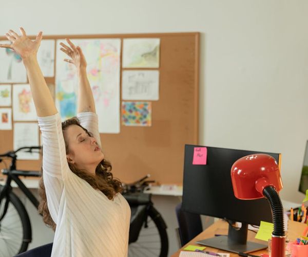 Person stretching comfortably at their office desk during a break.